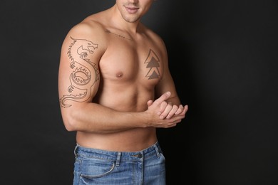 Image of Handsome man with beautiful tattoo sketches on black background, closeup