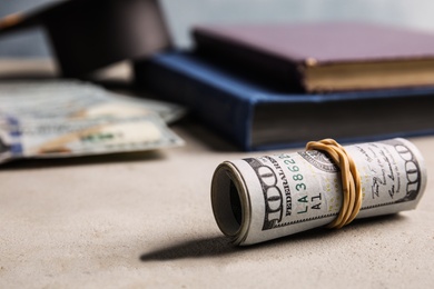 Photo of Dollar banknotes and student graduation hat on grey table. Tuition fees concept