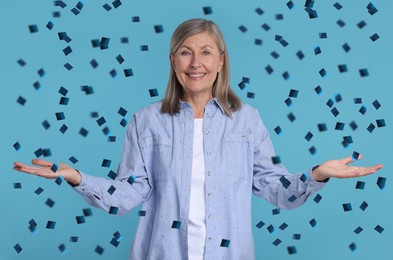 Happy woman and flying confetti on light blue background