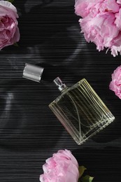 Luxury perfume and floral decor on dark background, flat lay