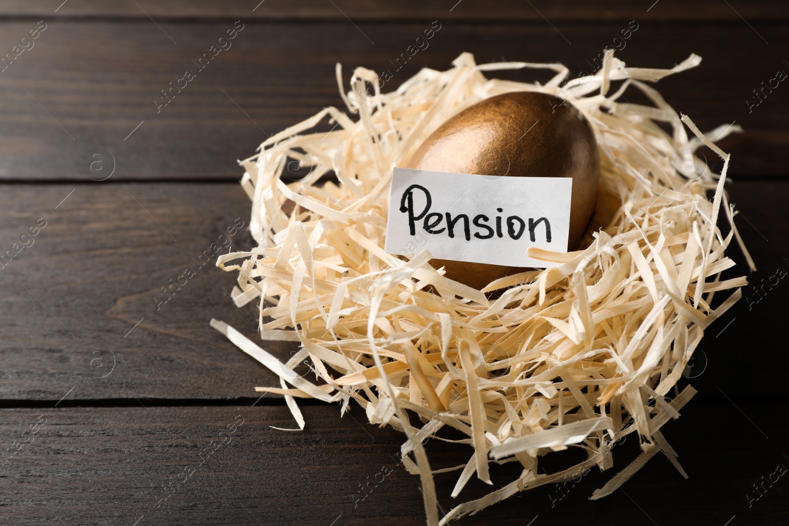 Photo of Golden egg and card with word PENSION in nest on wooden background