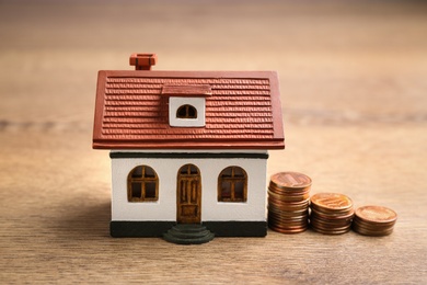 House model and coins on wooden table. Money saving concept