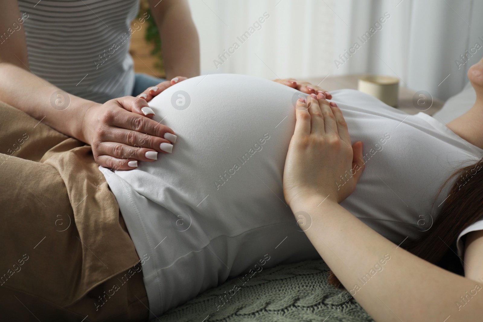 Photo of Doula taking care of pregnant woman indoors, closeup. Preparation for child birth