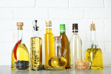Photo of Different cooking oils in bottles on grey table