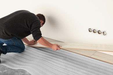 Photo of Professional worker installing new laminate flooring. Space for text