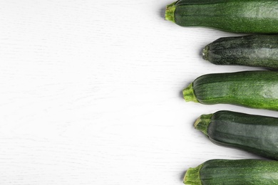 Photo of Fresh ripe green zucchinis on white wooden table, flat lay. Space for text