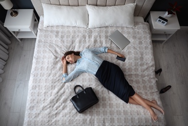 Photo of Exhausted businesswoman in office wear sleeping on bed at home after work, above view
