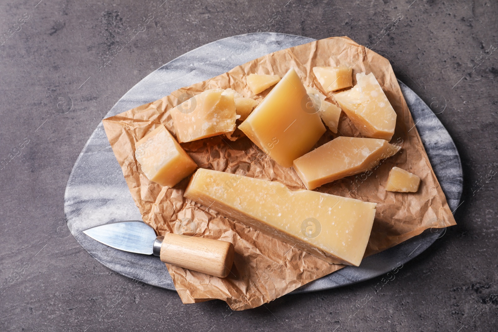 Photo of Marble board with delicious cheese on grey table, top view