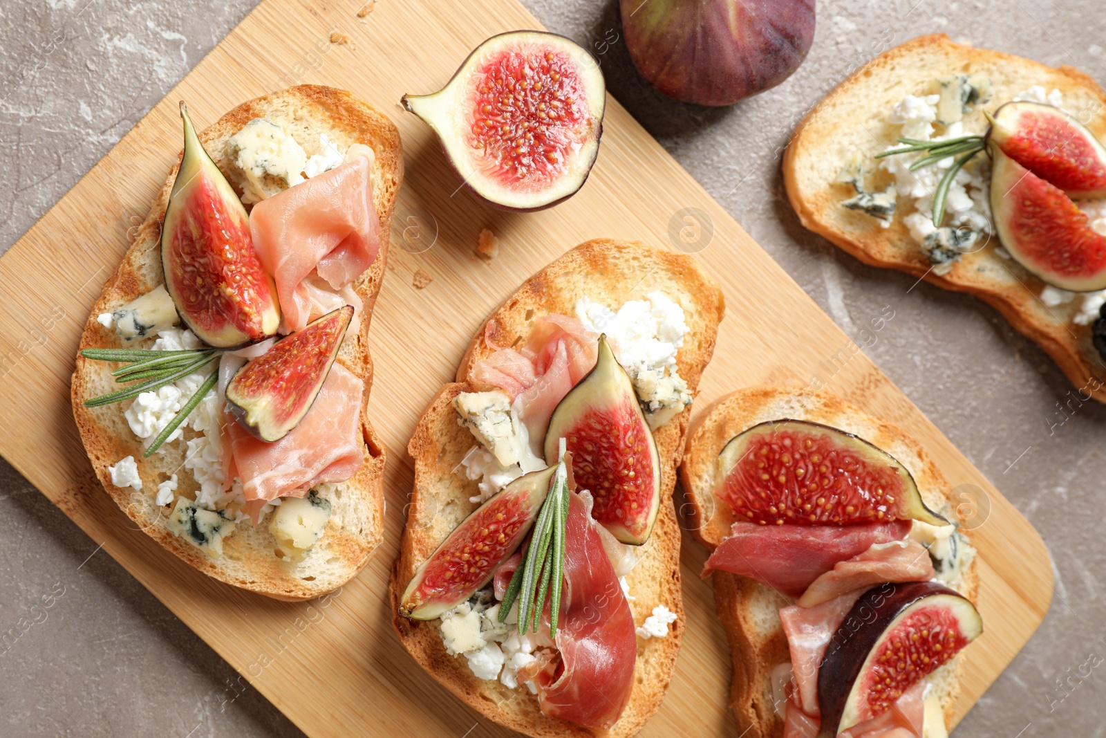 Photo of Bruschettas with cheese, prosciutto and figs served on marble table, top view