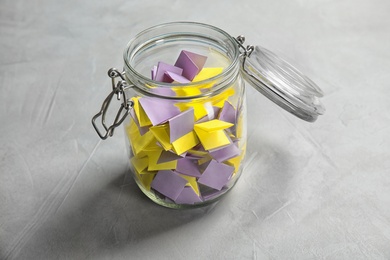 Photo of Colorful paper pieces for lottery in glass jar on table