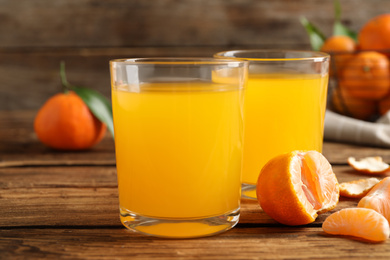 Glasses of fresh tangerine juice and fruits on wooden table