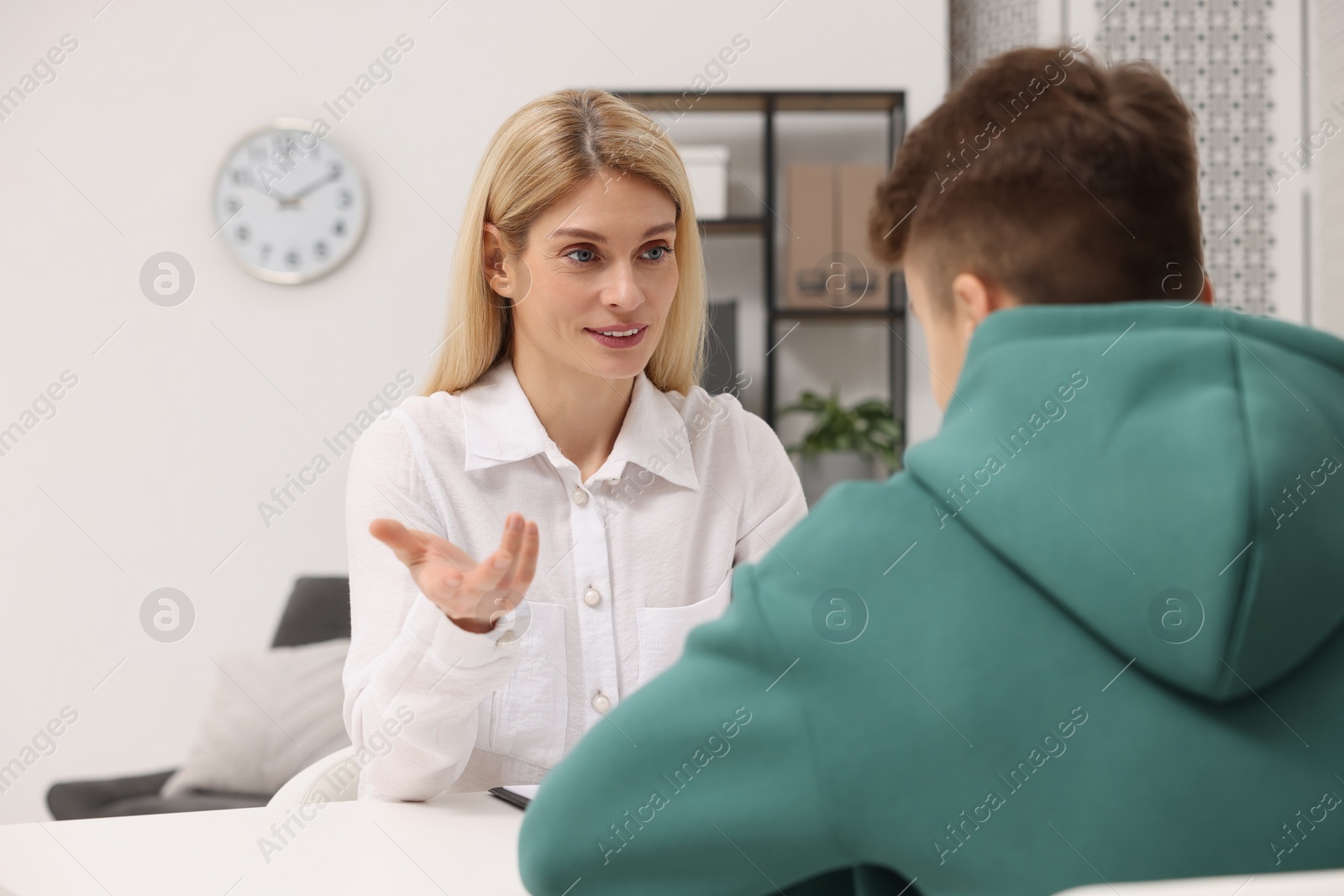 Photo of Psychologist working with teenage boy at table in office