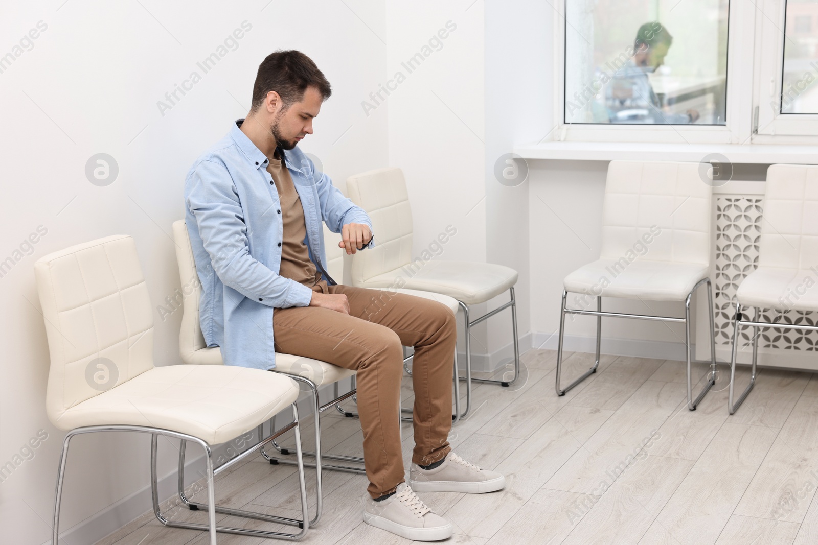 Photo of Man looking at wrist watch and waiting for job interview indoors