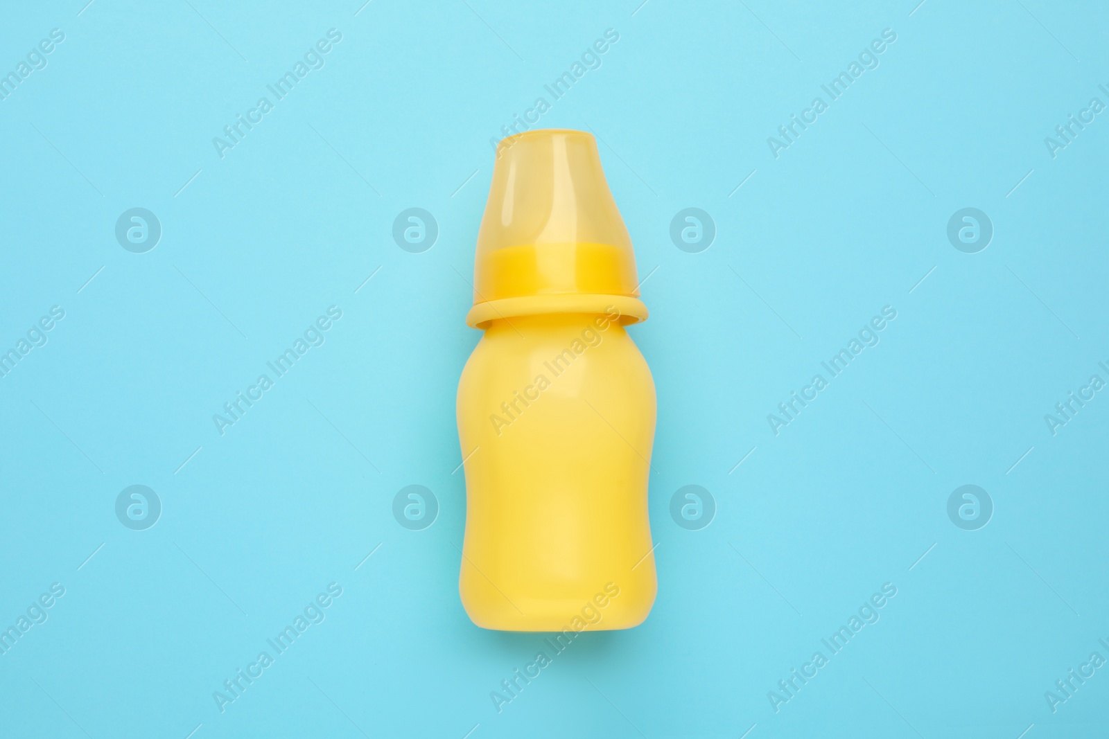 Photo of Feeding bottle with infant formula on light blue background, top view