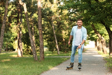 Photo of Young man roller skating in summer park. Space for text