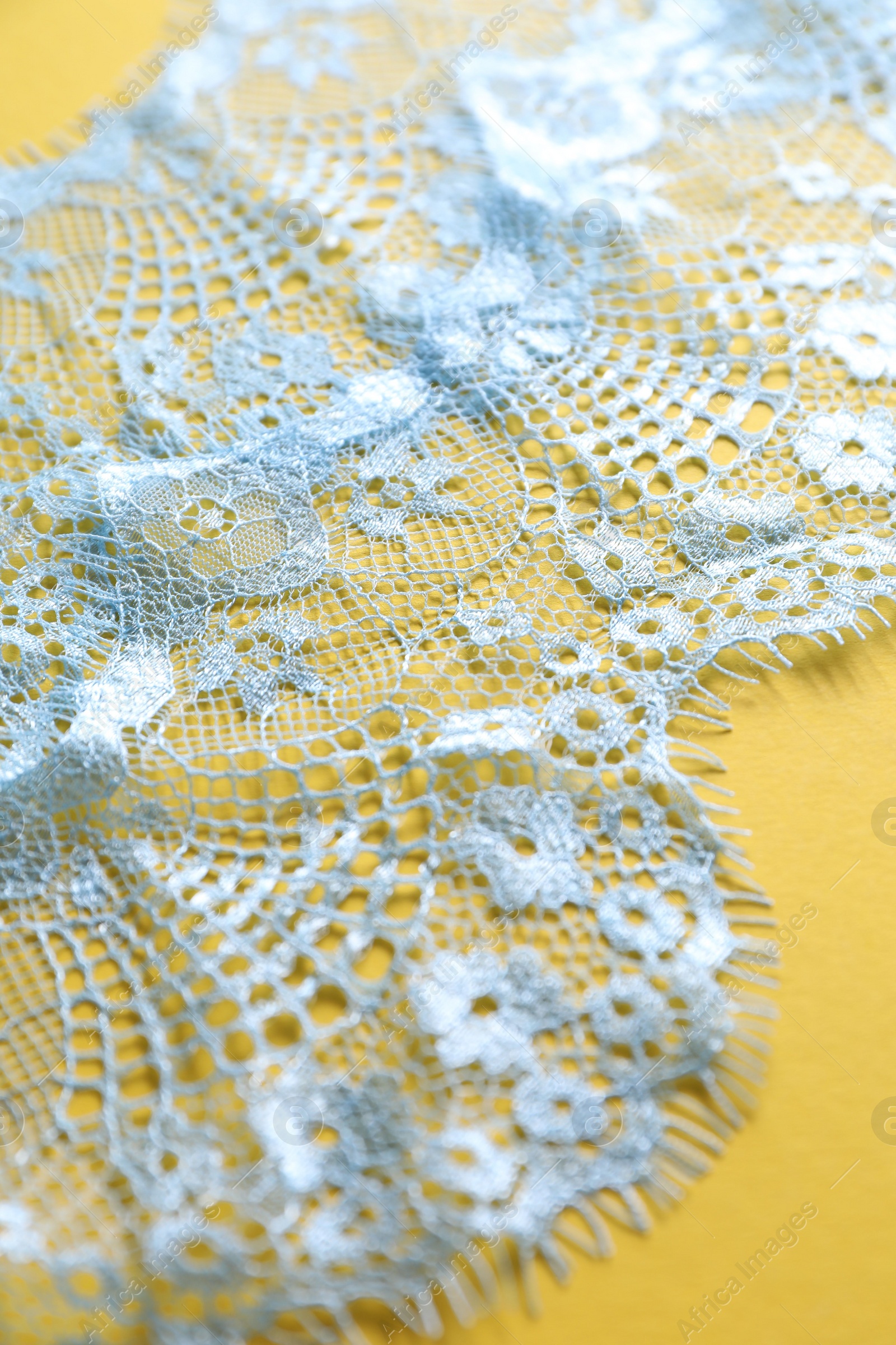 Photo of Light blue lace on yellow background, closeup