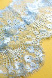 Photo of Light blue lace on yellow background, closeup