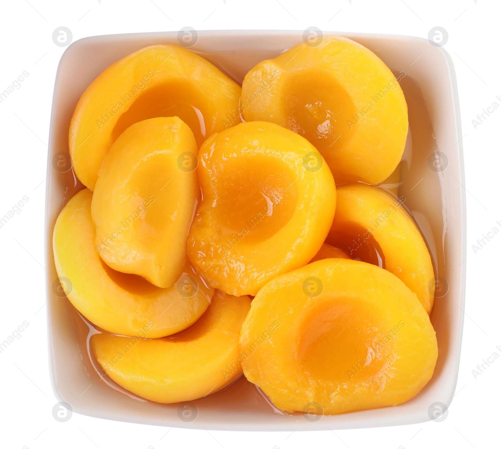 Photo of Halves of canned peaches in bowl isolated on white, top view