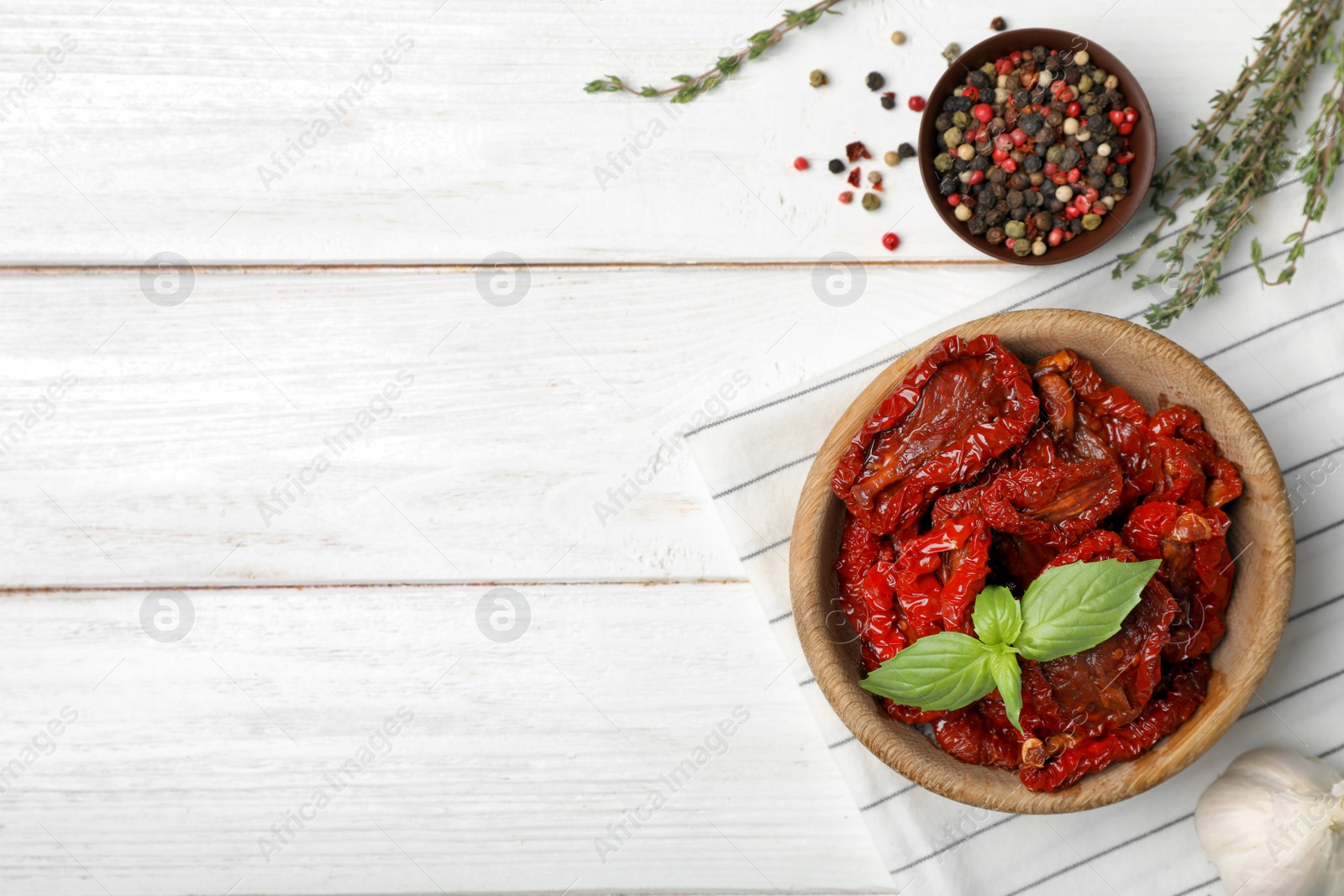 Photo of Bowl of sun dried tomatoes on wooden table, flat lay composition with space for text