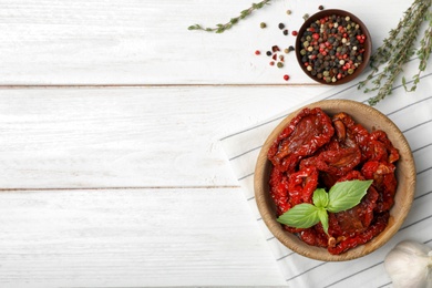 Bowl of sun dried tomatoes on wooden table, flat lay composition with space for text