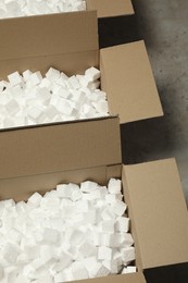 Photo of Many open cardboard boxes with pieces of polystyrene foam on grey floor