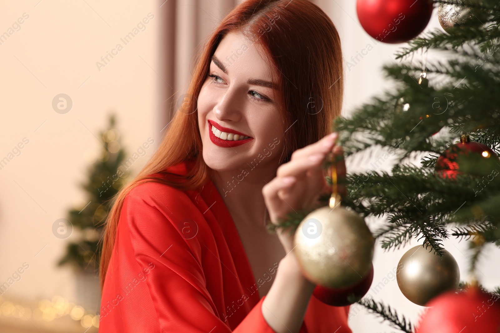 Photo of Beautiful young woman decorating Christmas tree at home