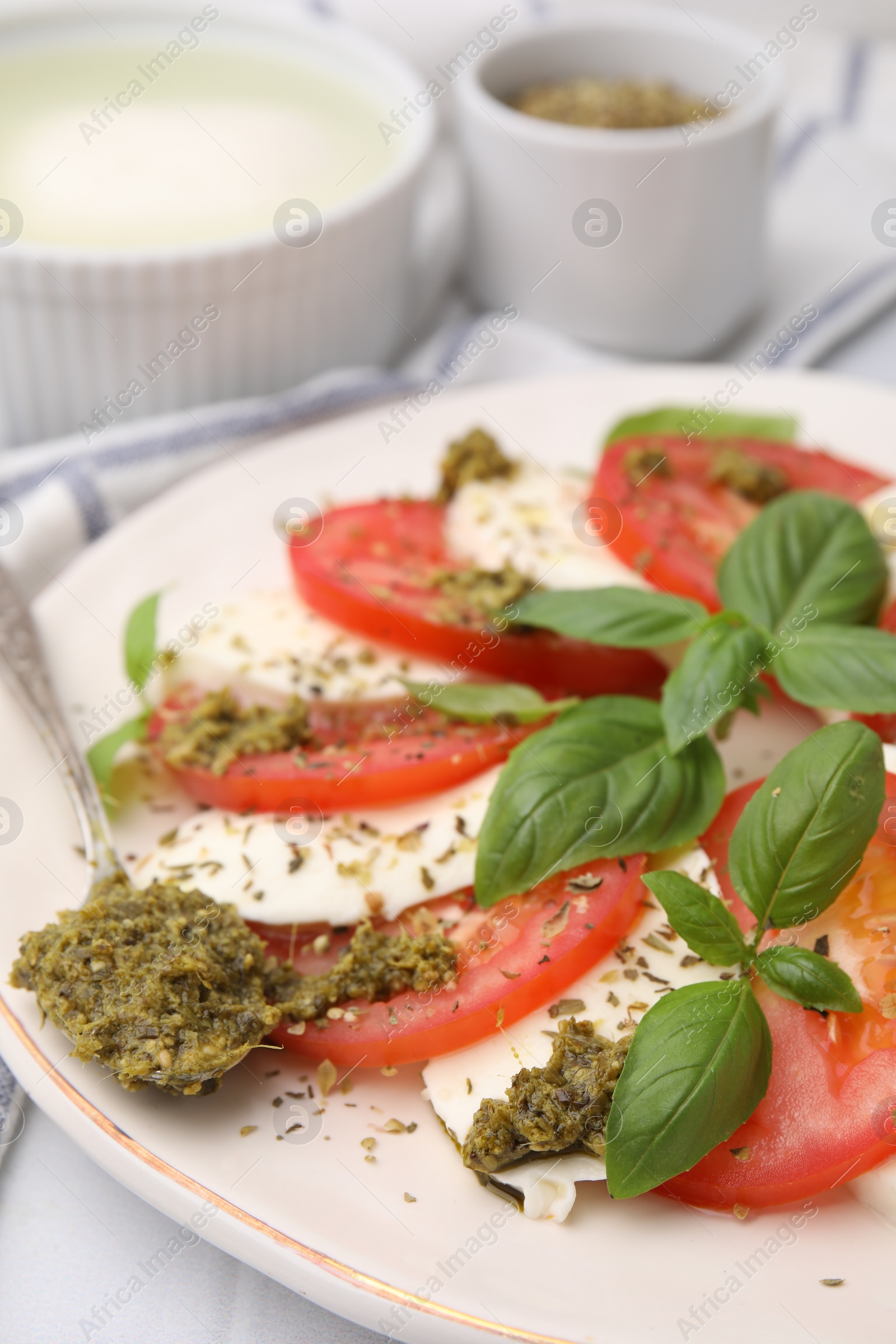 Photo of Plate of delicious Caprese salad with pesto sauce on table, closeup