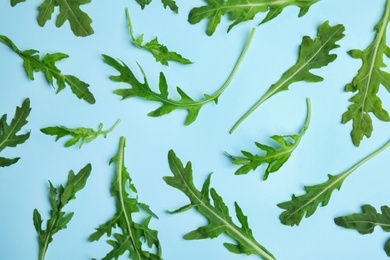 Photo of Fresh arugula on light blue background, flat lay