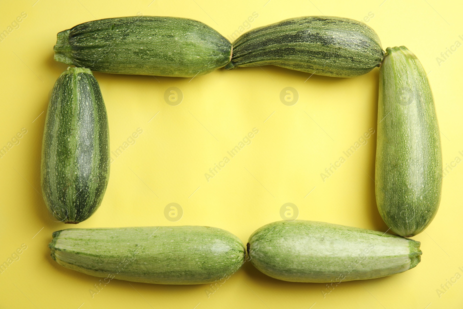 Photo of Fresh ripe green zucchinis on yellow background, flat lay. Space for text