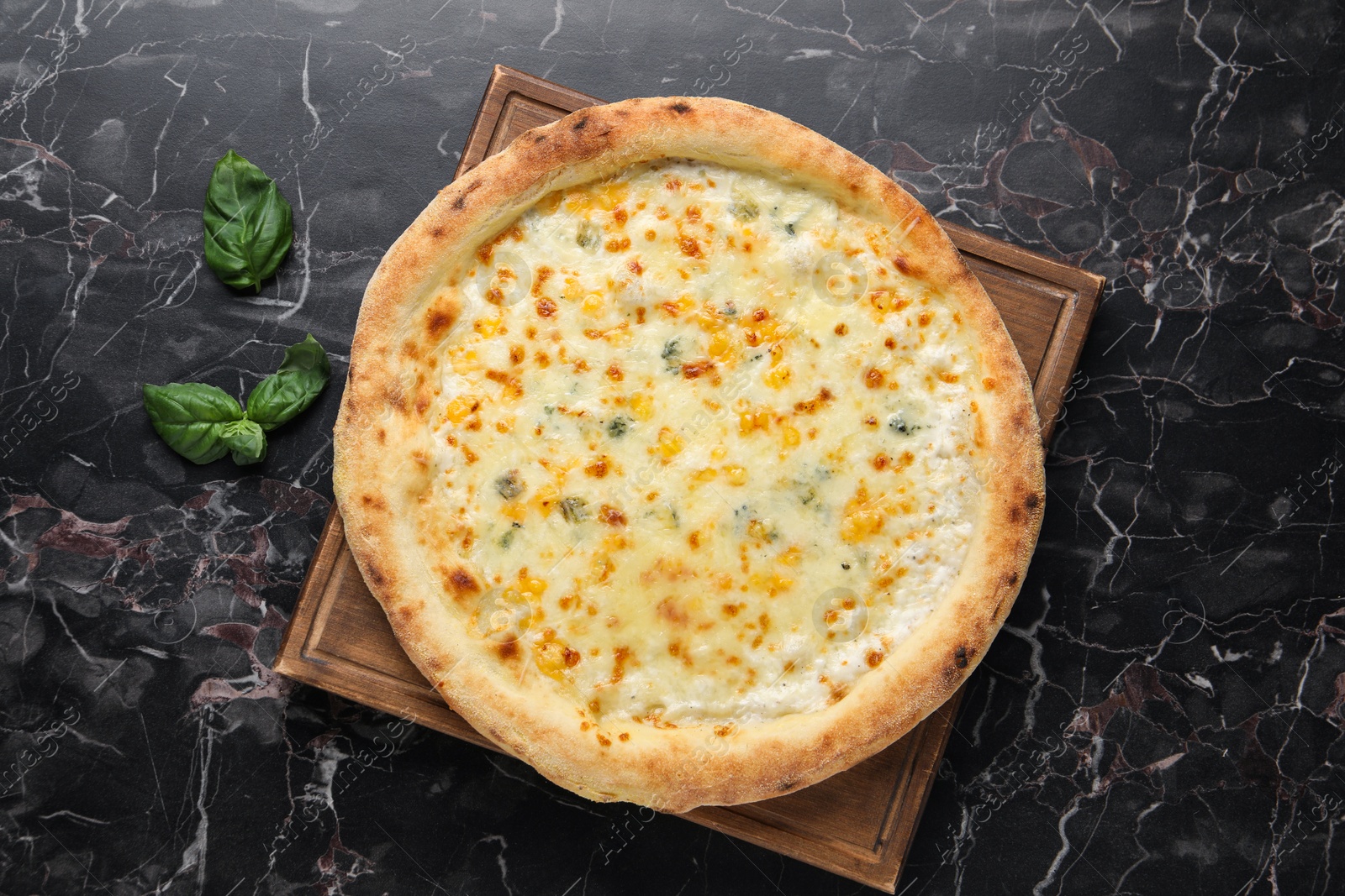 Photo of Delicious cheese pizza and basil on black marble table, flat lay