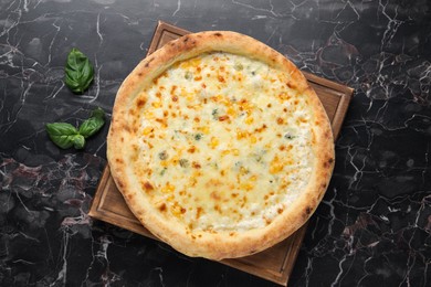 Photo of Delicious cheese pizza and basil on black marble table, flat lay