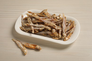 Plate of tasty dried anchovies on light wooden table