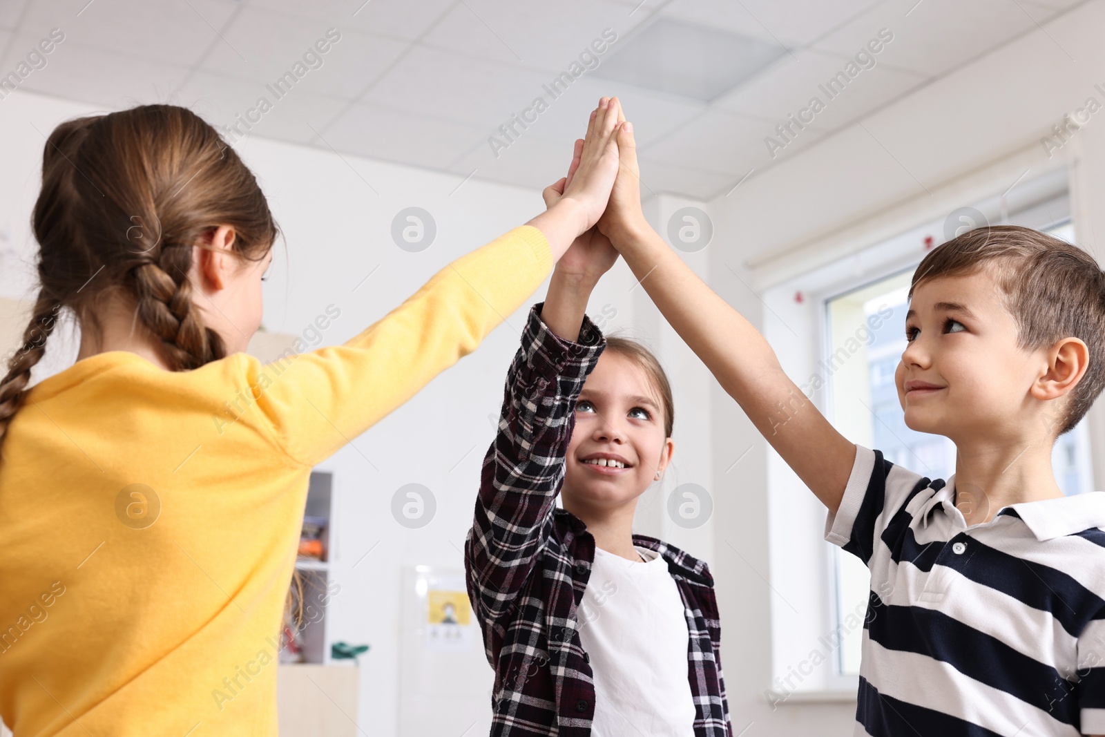 Photo of Happy children giving high five at school