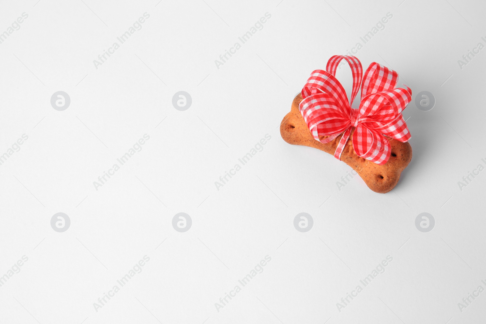 Photo of Bone shaped dog cookie with bow on white background, above view. Space for text