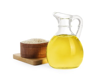 Glass jug of fresh sesame oil and bowl with seeds isolated on white