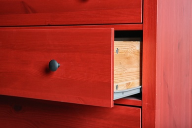 Photo of Red chest of drawers, closeup. Stylish furniture for wardrobe room