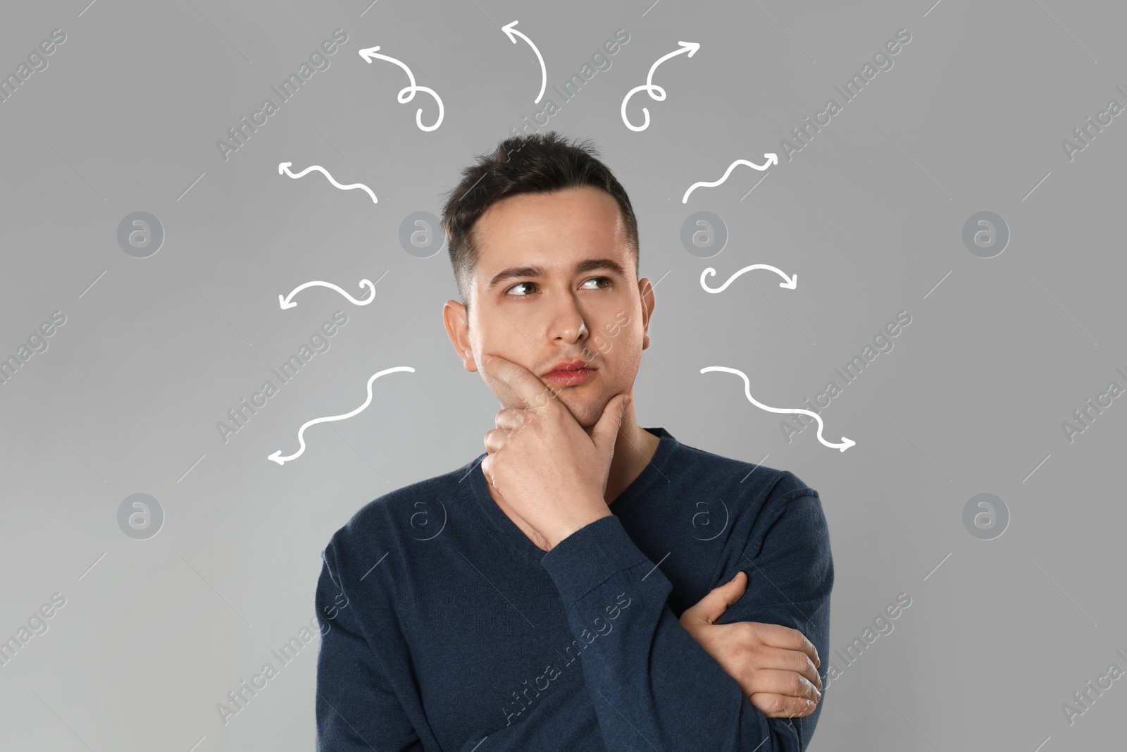 Image of Choice in profession or other areas of life, concept. Making decision, thoughtful young man surrounded by drawn arrows on grey background