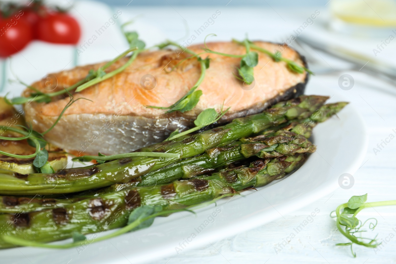 Photo of Tasty salmon steak served with grilled asparagus on plate, closeup