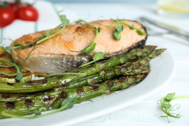 Photo of Tasty salmon steak served with grilled asparagus on plate, closeup