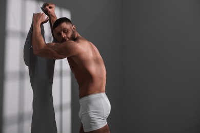 Photo of Young man in stylish white underwear near grey wall. Space for text