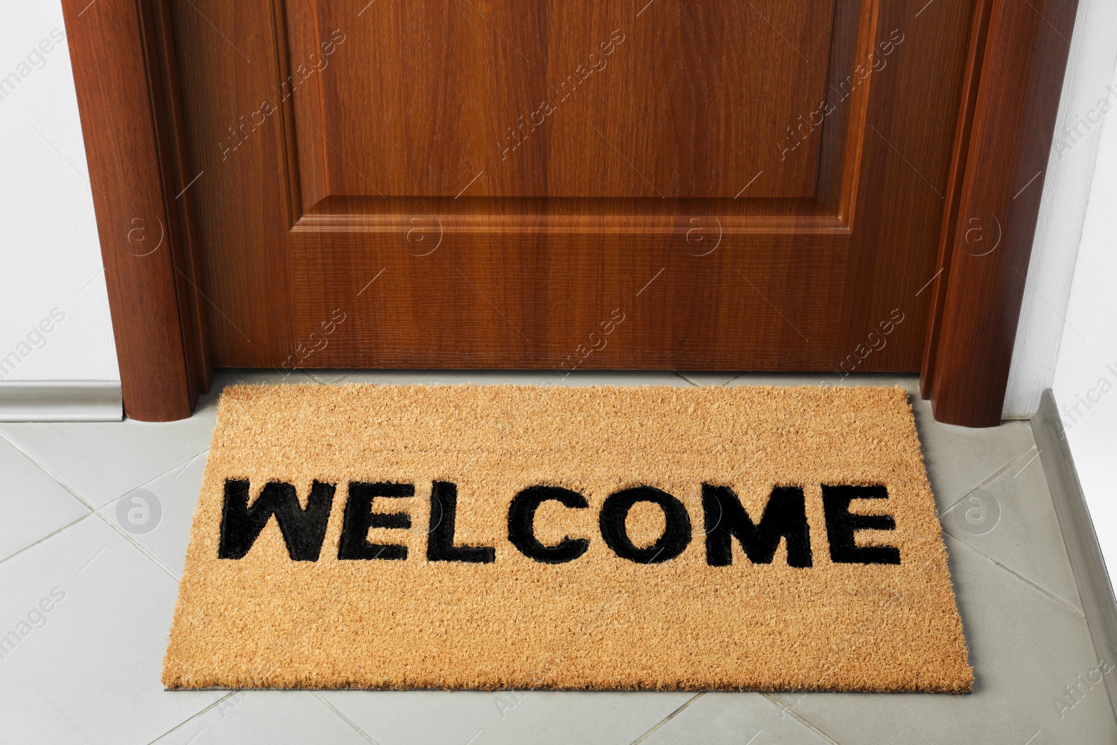 Photo of Door mat with word Welcome on floor near entrance