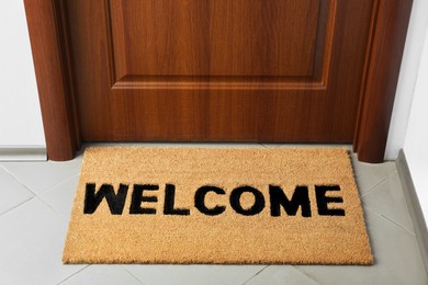 Door mat with word Welcome on floor near entrance