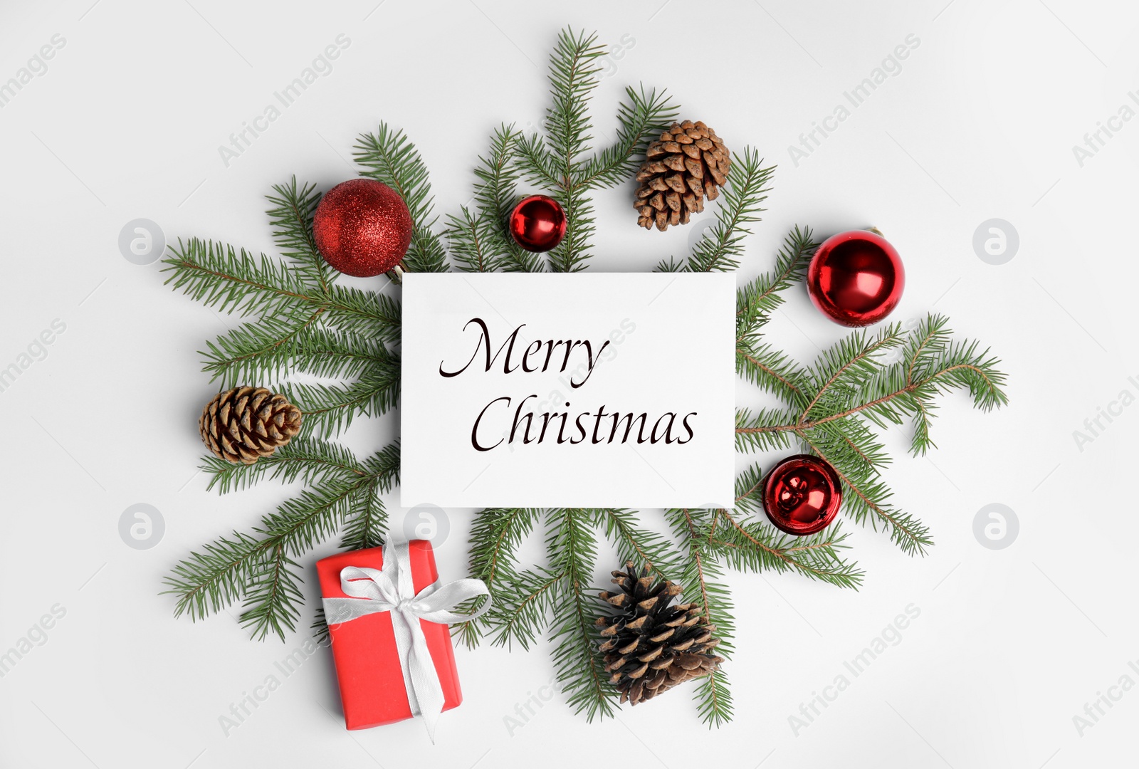 Image of Greeting card with phrase Merry Christmas, gift box, fir tree branches and beautiful festive decor on white background, flat lay