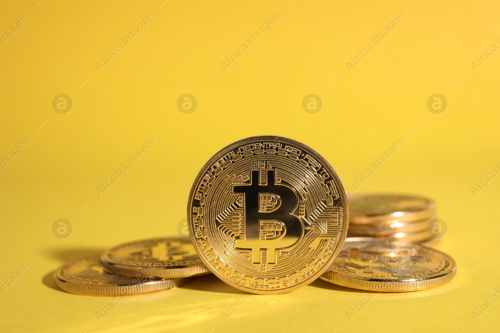 Photo of Shiny bitcoins on yellow background. Digital currency