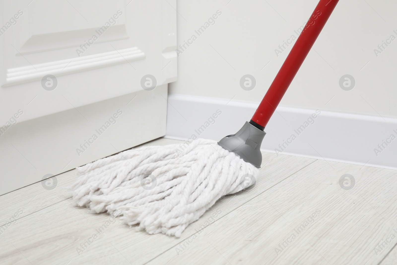 Photo of Cleaning white parquet floor with mop, closeup