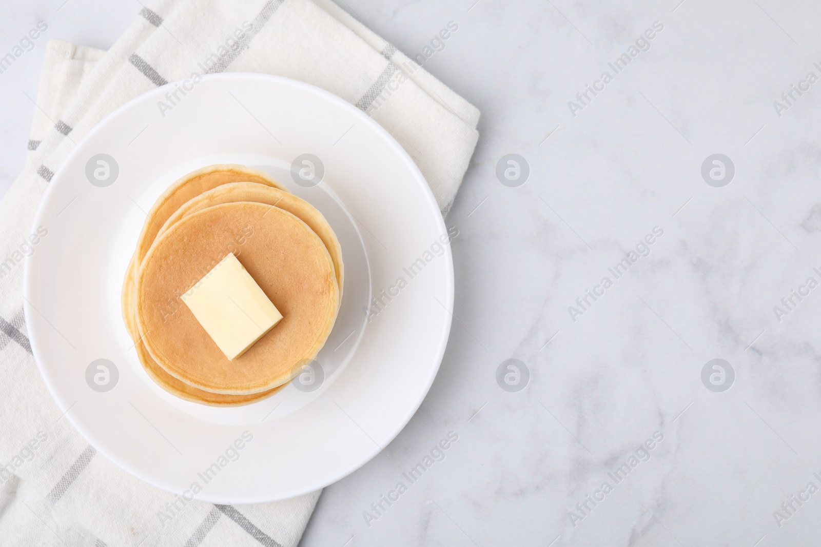 Photo of Delicious pancakes with butter on marble table, top view. Space for text