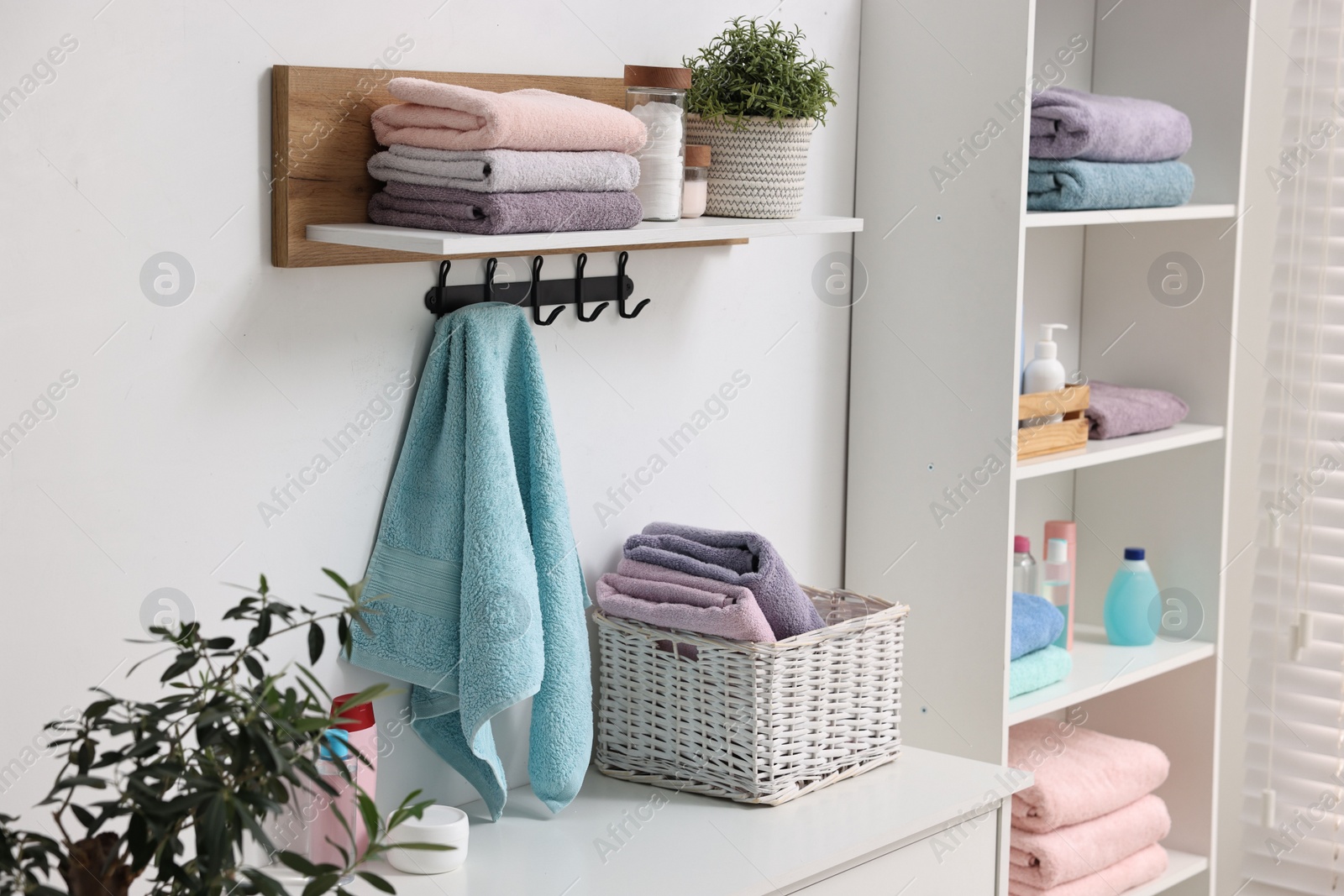 Photo of Fresh towels, laundry basket and toiletries on chest of drawers indoors