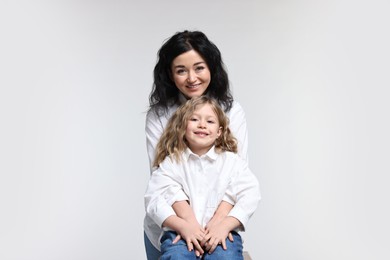 Beautiful mother with little daughter on white background