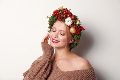 Photo of Beautiful young woman wearing Christmas wreath on white background