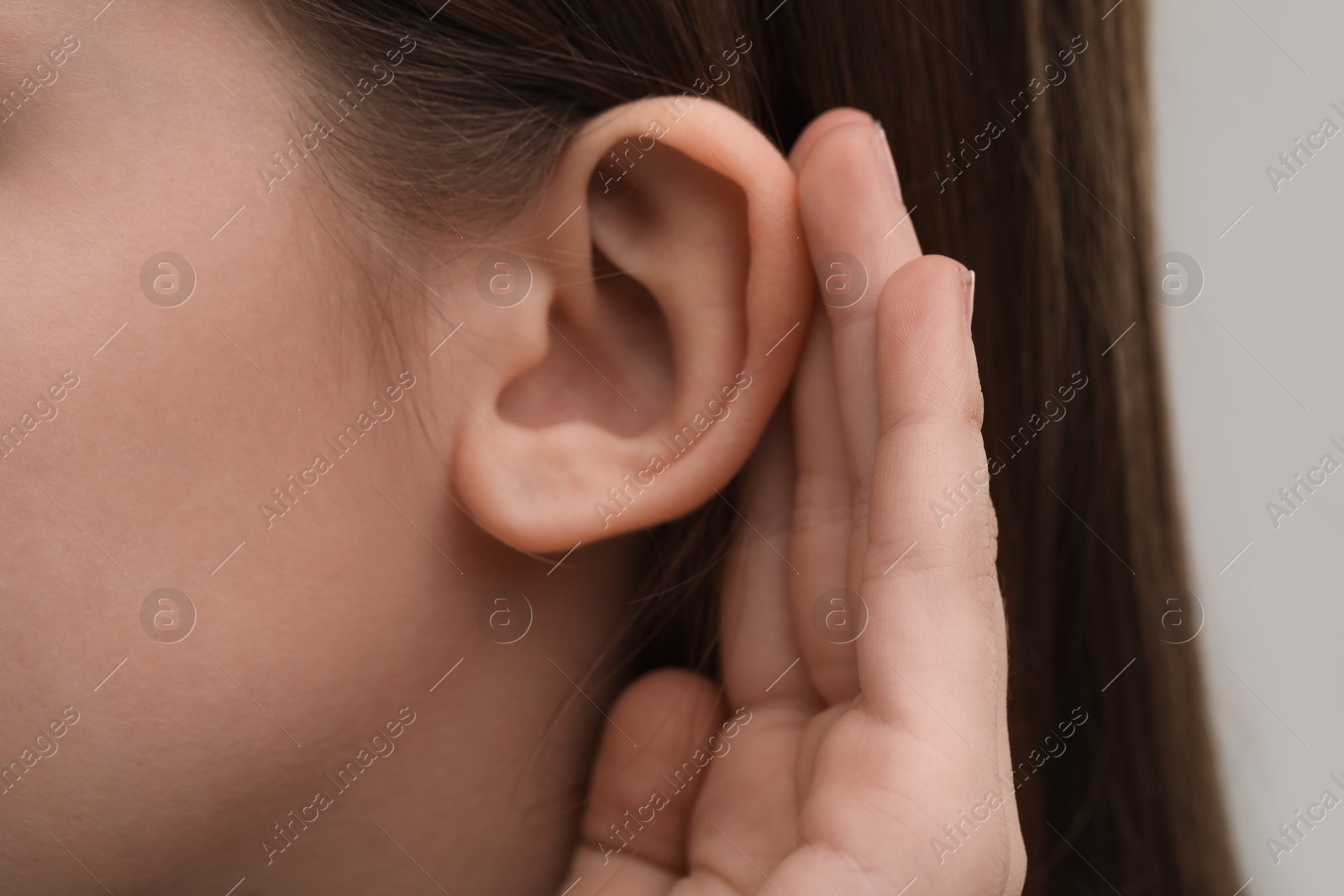 Photo of Little girl with hearing problem on grey background, closeup